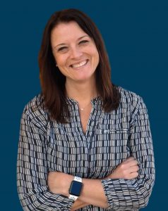 Laura Hess smiling in front of a navy blue background.