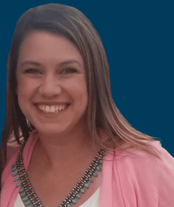 Alyse Fieldgrove smiling in front a a navy blue background.