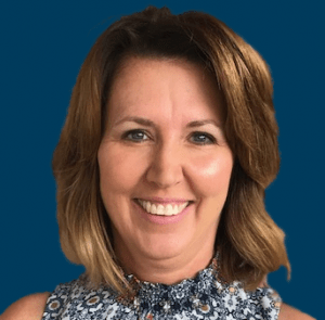 Kathy Oakes smiling in front of a navy blue background.