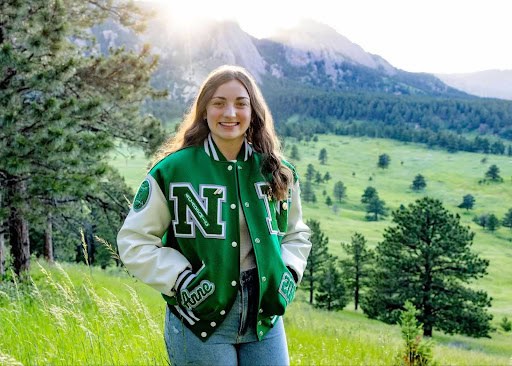 Anne Booth in front of mountains wearing a Niwot letter jacket smiling for the camera.