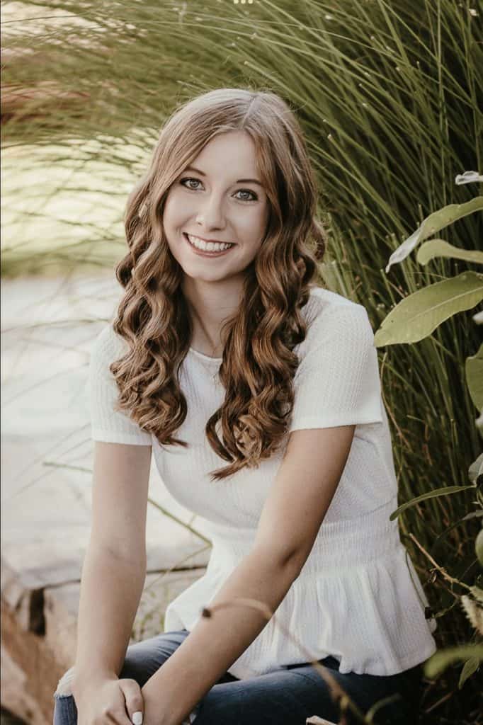 Laura Heuer, Skyline High School Graduate sitting on a bench smiling 