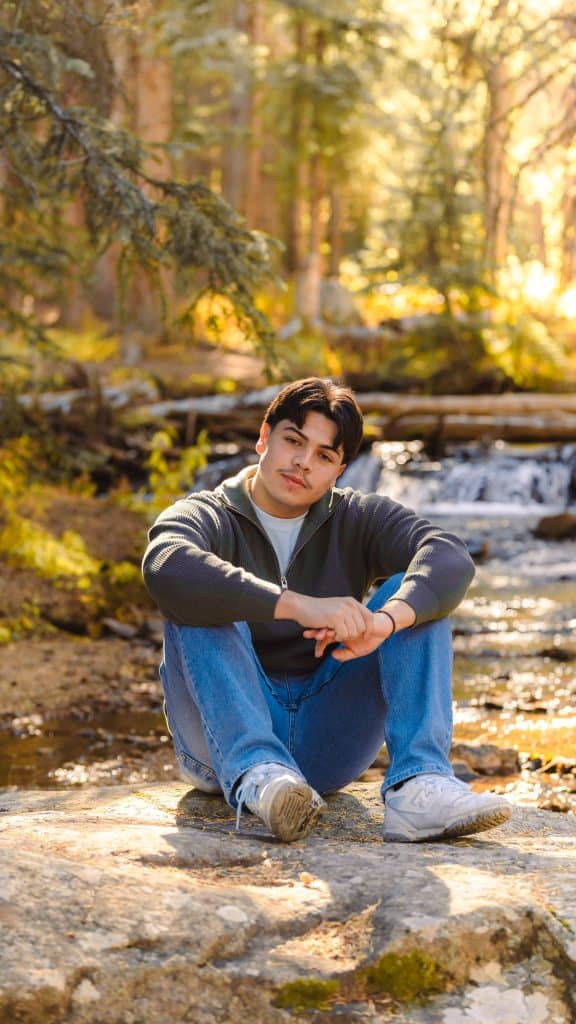Marcos Meza, Frederick High Graduate sitting on a rock next to the creek
