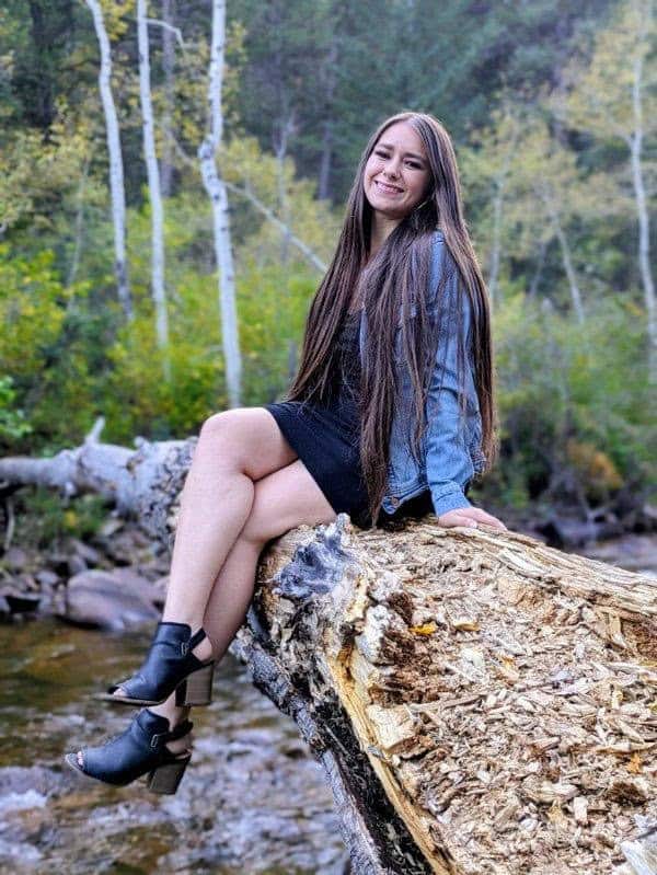 Jessayla Stiffler, New Meridian Graduate sitting on a tree smiling at the camera