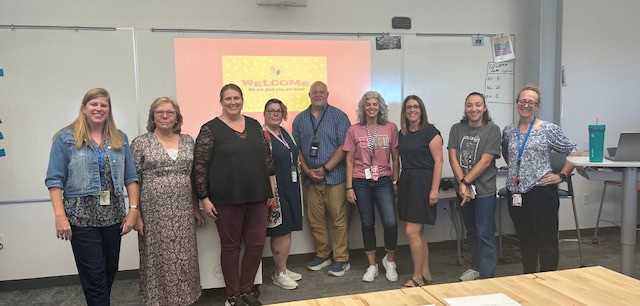 7 alternative education teachers and 2 instructors pose for picture in front of smartboard