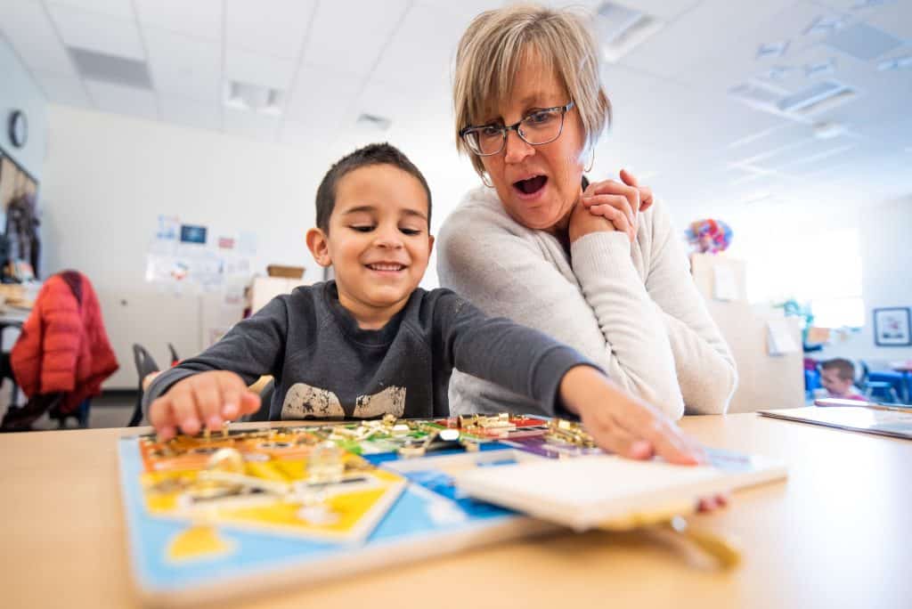 Preschool student and teacher working on STEM activity at desk.