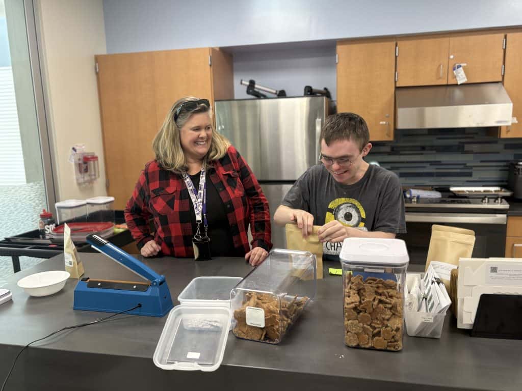 LSACE student and para smile while packaging dog treats.