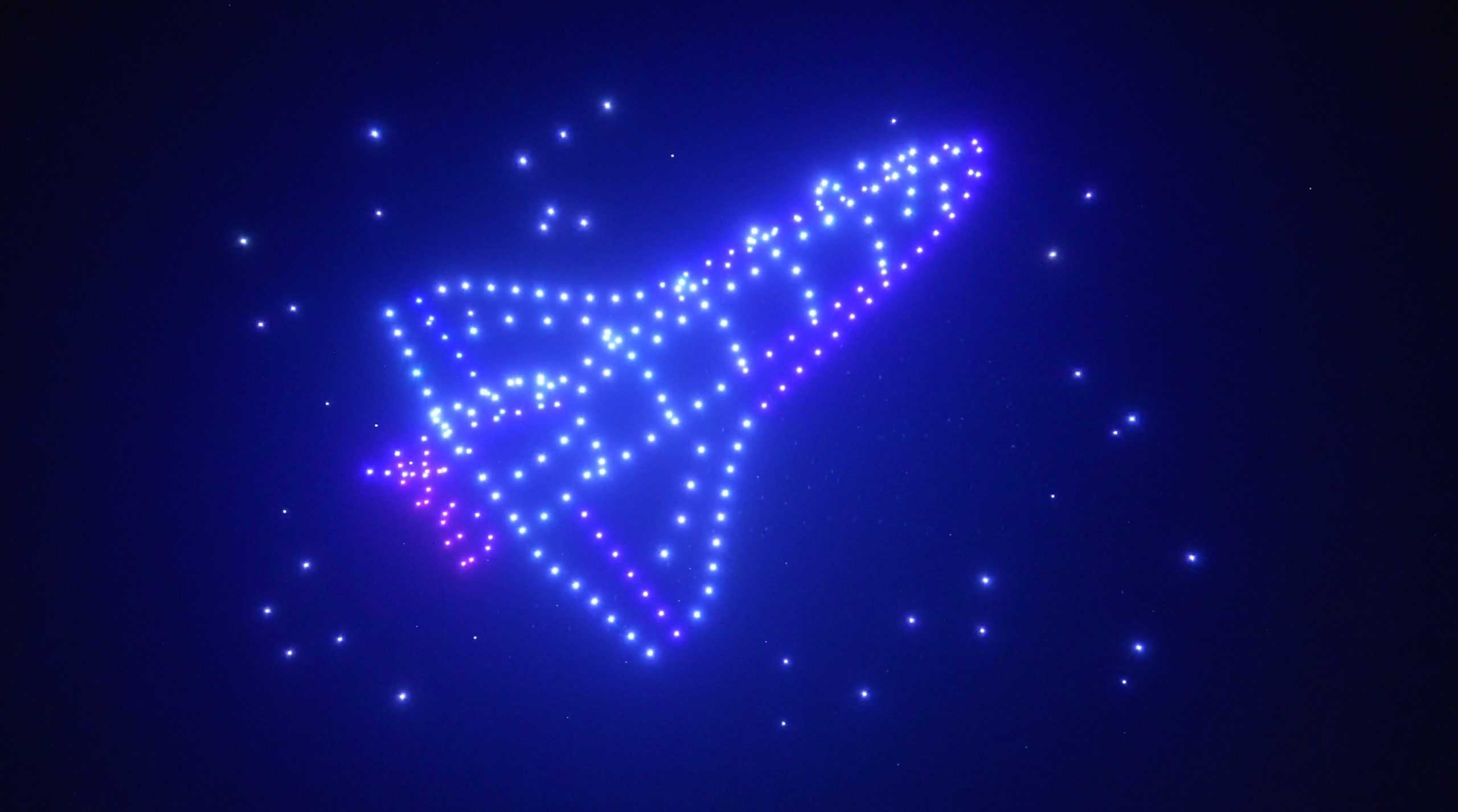 Un brillante diseño de estrellas multicolores que forma la silueta de una nave espacial contra el oscuro cielo nocturno.
