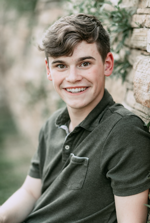 Dean Curtis, an Erie High Senior against a stone wall, wearing a dark polo shirt and looking directly at the camera.