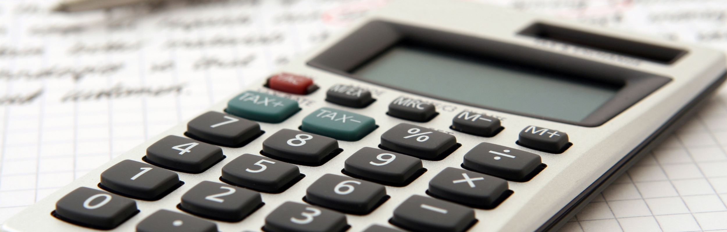 Primer plano de una calculadora sobre un fondo de papel milimetrado en el que se aprecian notas escritas a mano.
