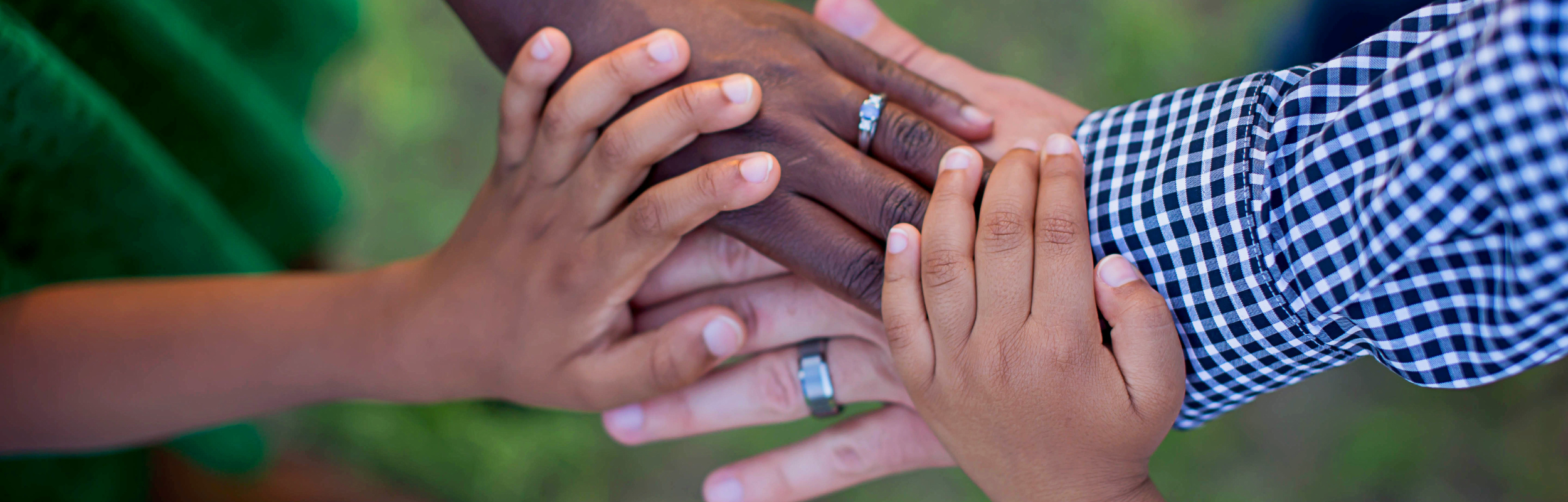A close-up of multiple hands of different skin tones stacking together, symbolizing unity and connection.