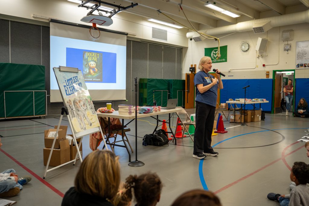 Katherine Applegate habla con los niños de Niwot Elementary, acompañada de libros y una pantalla de proyección en la que se muestra «Pocket Bear».