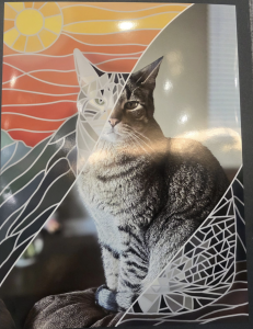 A stylized image of a tabby cat, half realistic and half geometric, with a colorful sunset background.