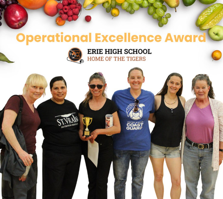 A group of six people poses together with a trophy, celebrating the Operational Excellence Award at Erie High School.